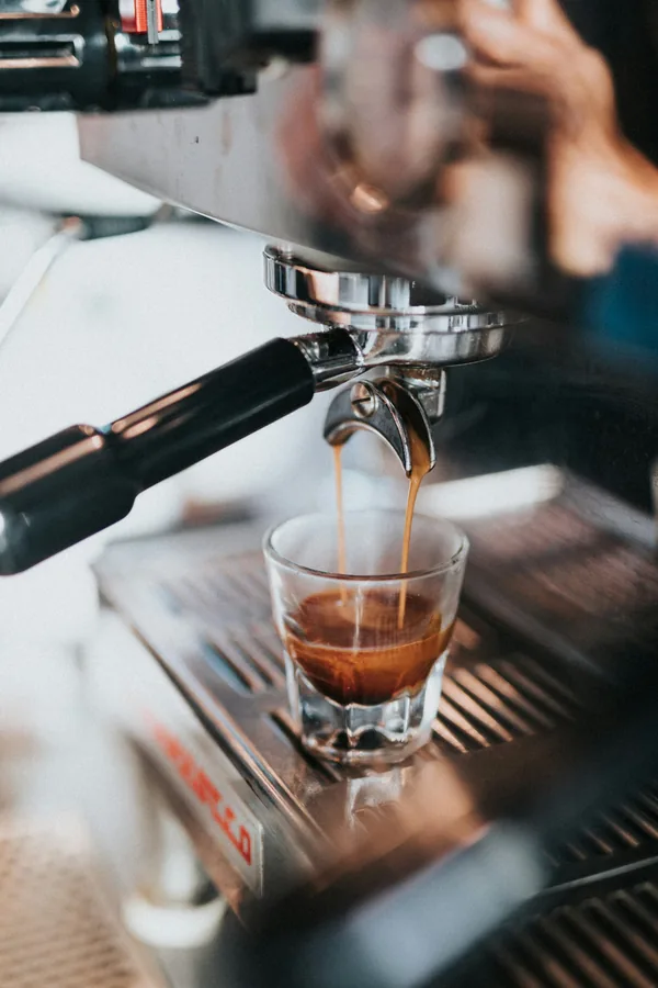 A double shot of espresso pouring into a white cup